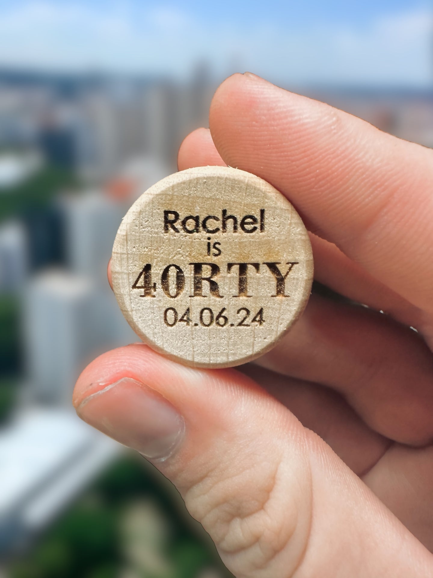 a person holding a wooden magnet with the words rachel is forty on it